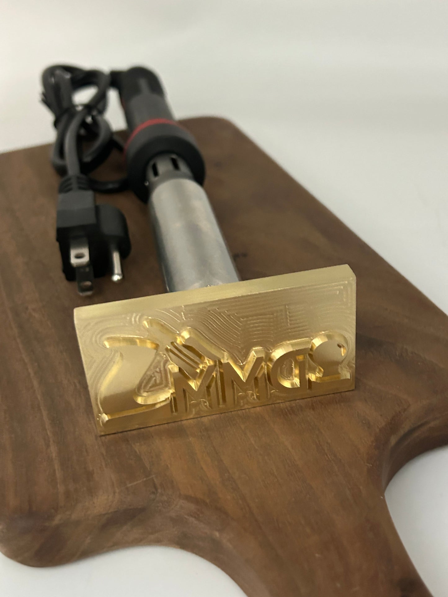Cutting board with a brass stamp and electric heating element on a white background