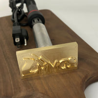 Cutting board with a brass stamp and electric heating element on a white background