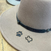 A close-up of a cowboy hat featuring custom miniature branding iron marks in the shape of a paw and a state outline.
